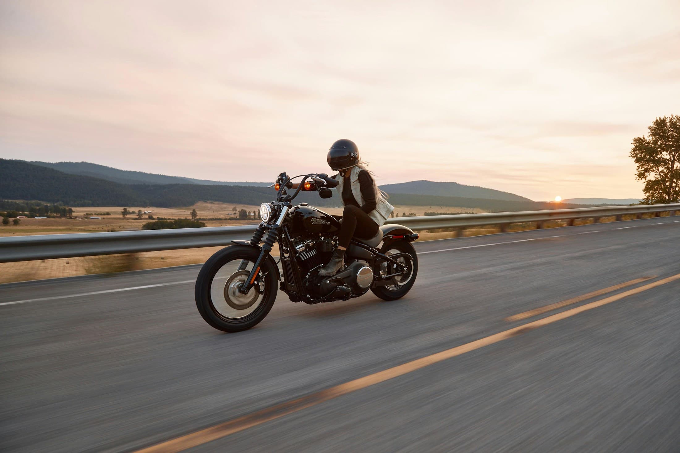 Motorcyclist riding confidently on an open road at sunset